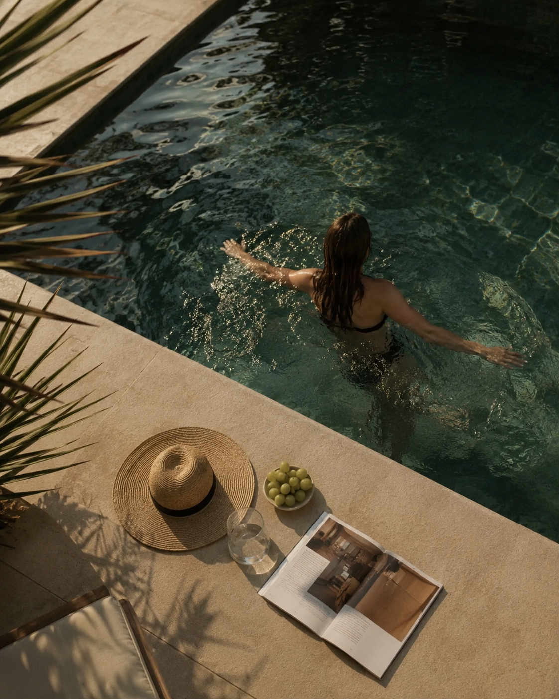 Guest swimming in a Mediterranean hotel pool surrounded by natural stone and tropical landscaping