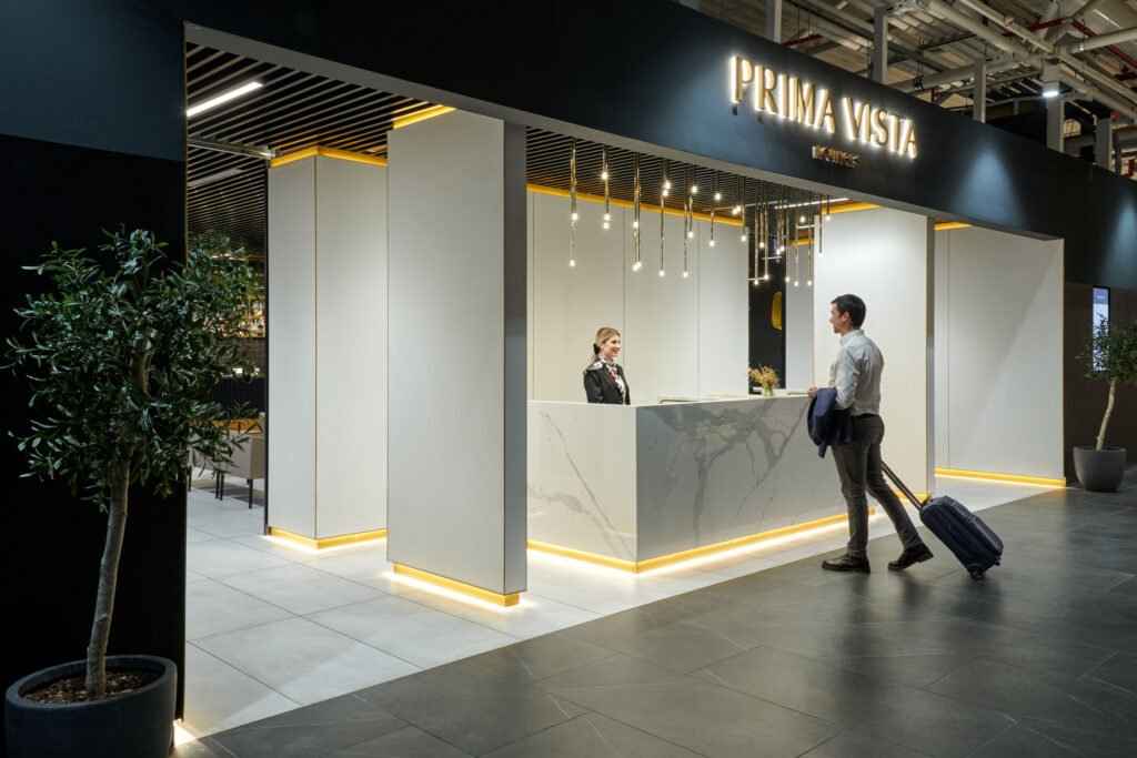Entrance to Prima Vista Domus Lounge at Rome Fiumicino Airport, with illuminated signage, pale columns and a veined reception desk.