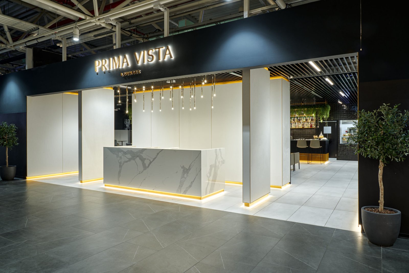 The elegant entrance of Prima Vista Lounge, featuring minimalist design, soft lighting, and a welcoming marble reception desk, by Indy Blue Studio.