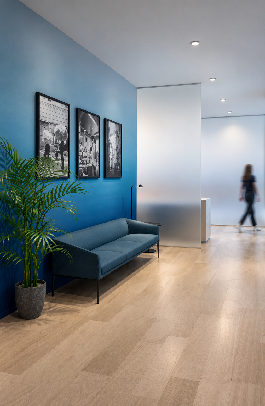 Blue seating area in a hotel VIP lounge designed by Indy Blue Studio, with framed photographs, a palm and a guest in the background