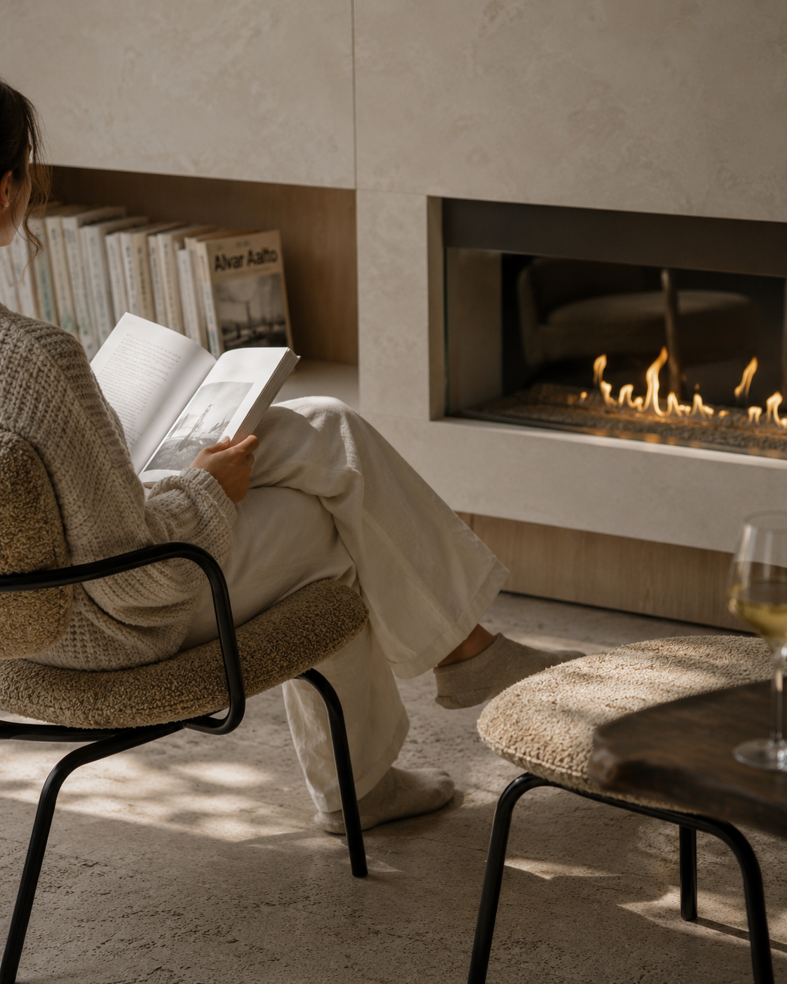 Hotel guest reading beside a fireplace in a premium Mediterranean hotel interior